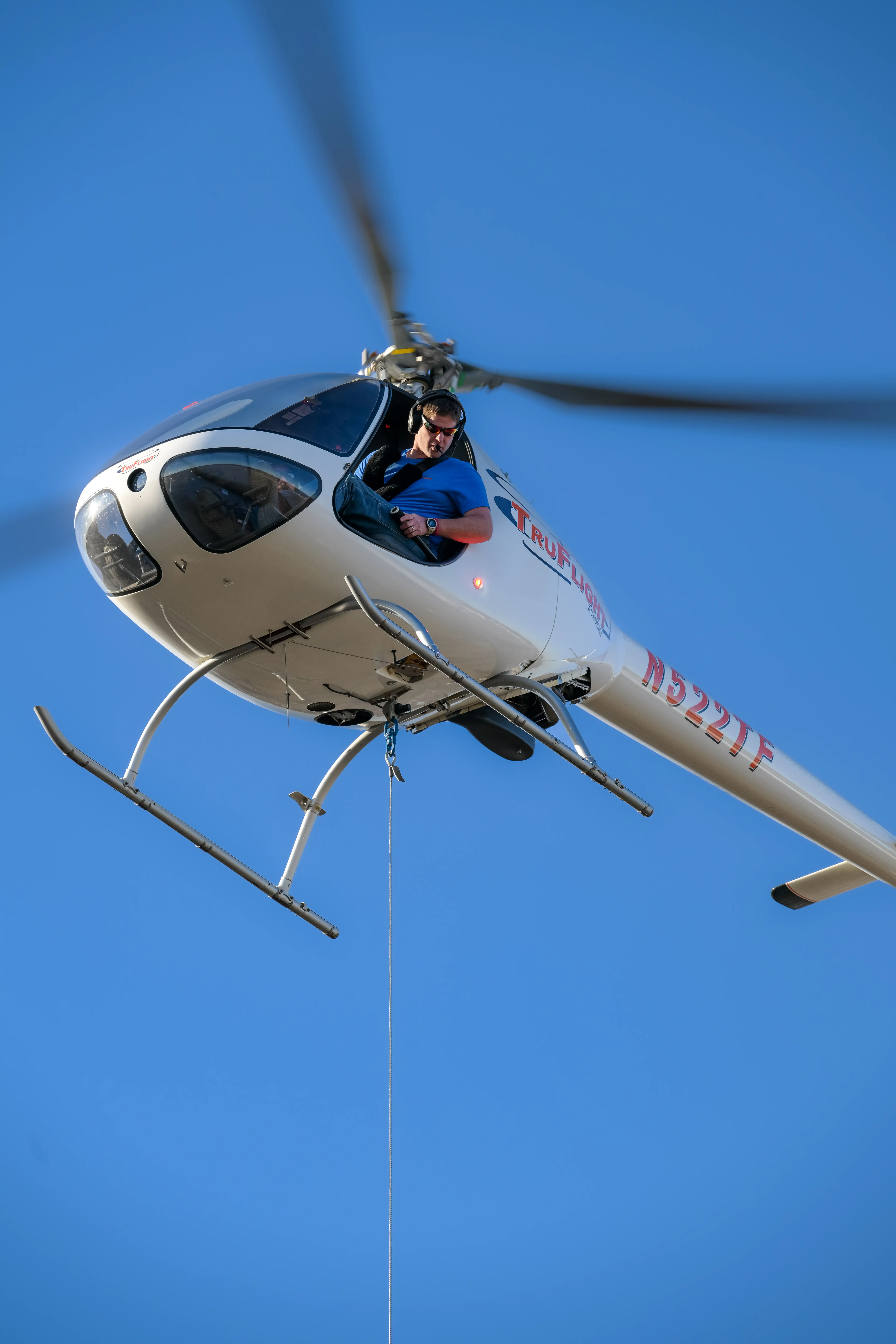 Low angle view of helicopter flying with cable attached to the bottom