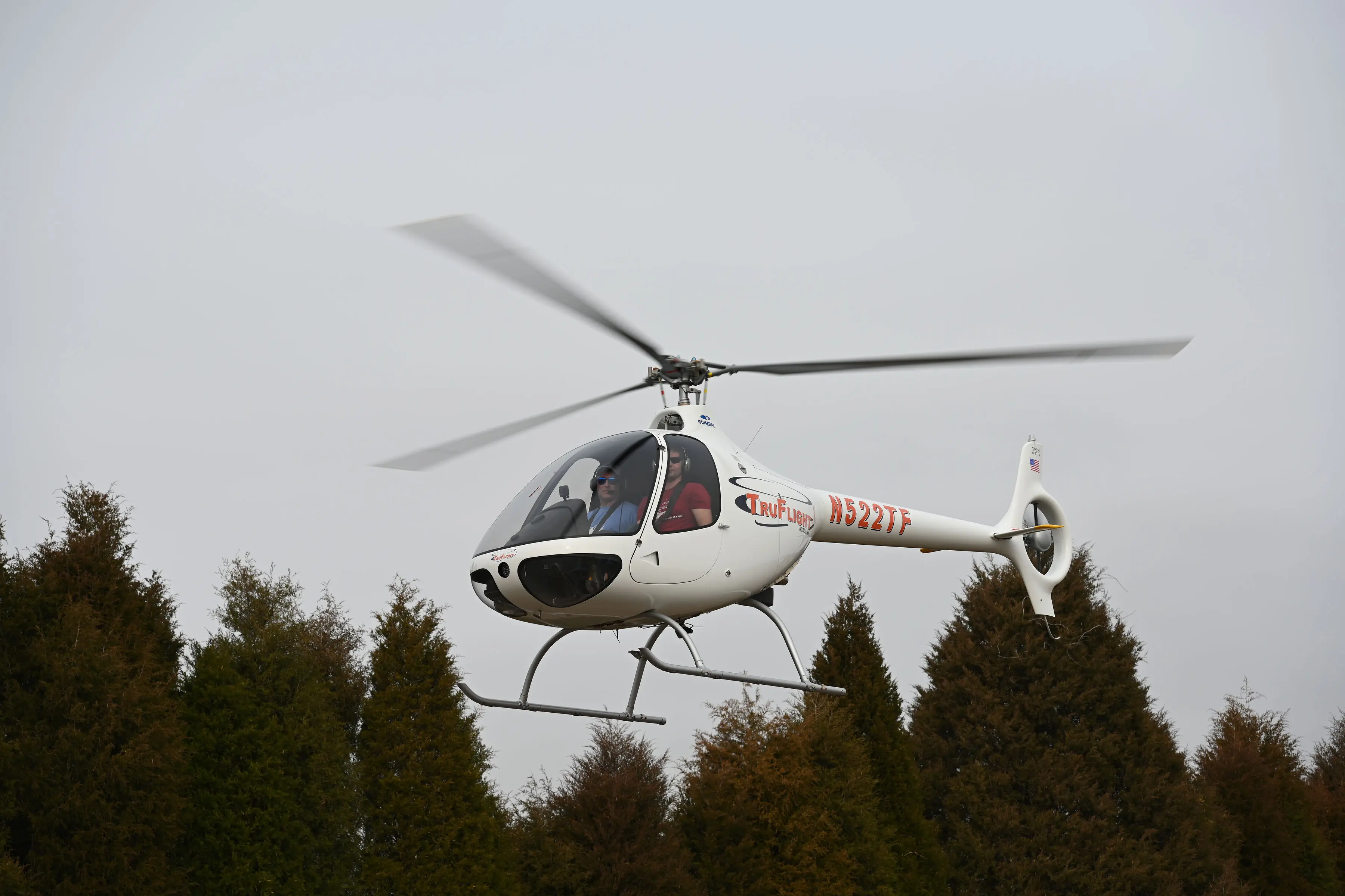 Helicopter flying with trees in the background